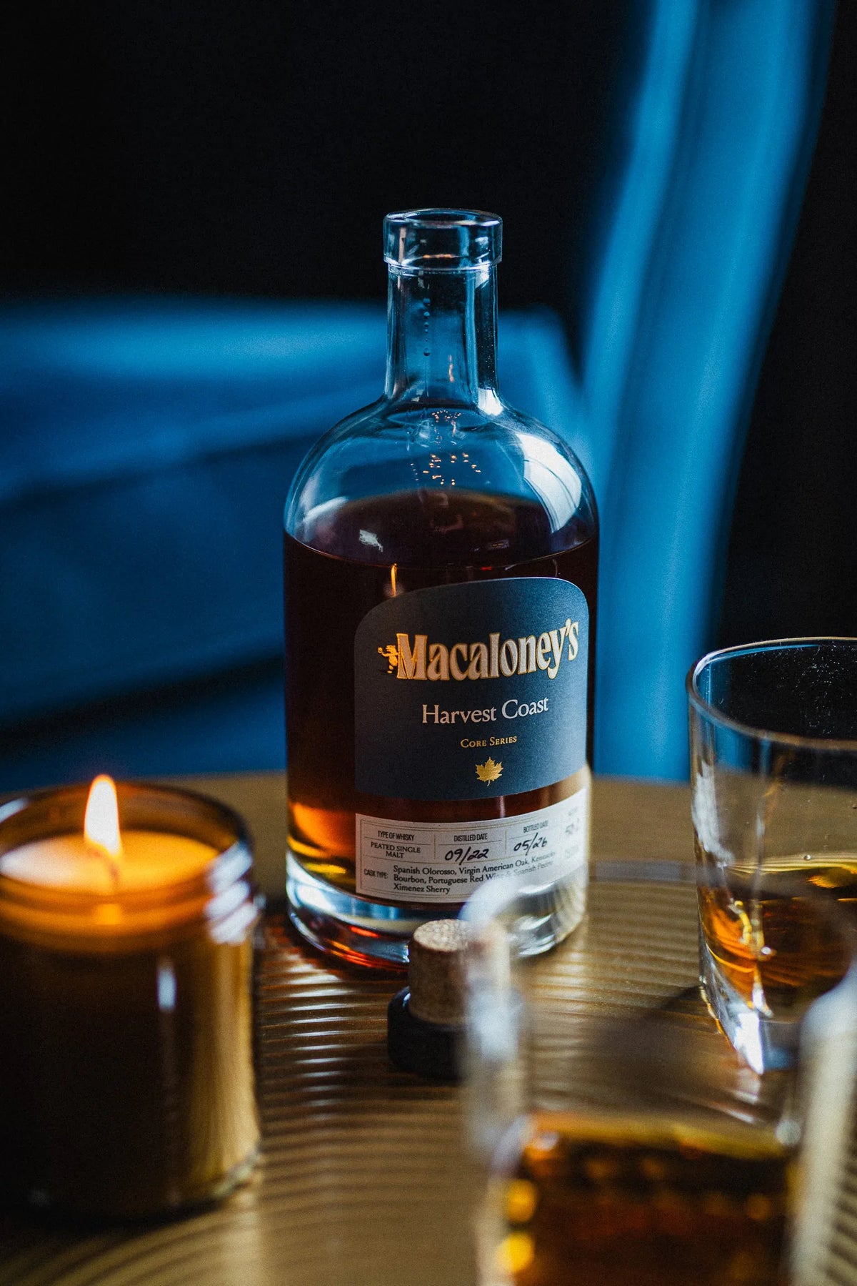 Macaloney's Harvest Coast heavily peated sherry cask single malt whisky by candlelight with rocks glasses