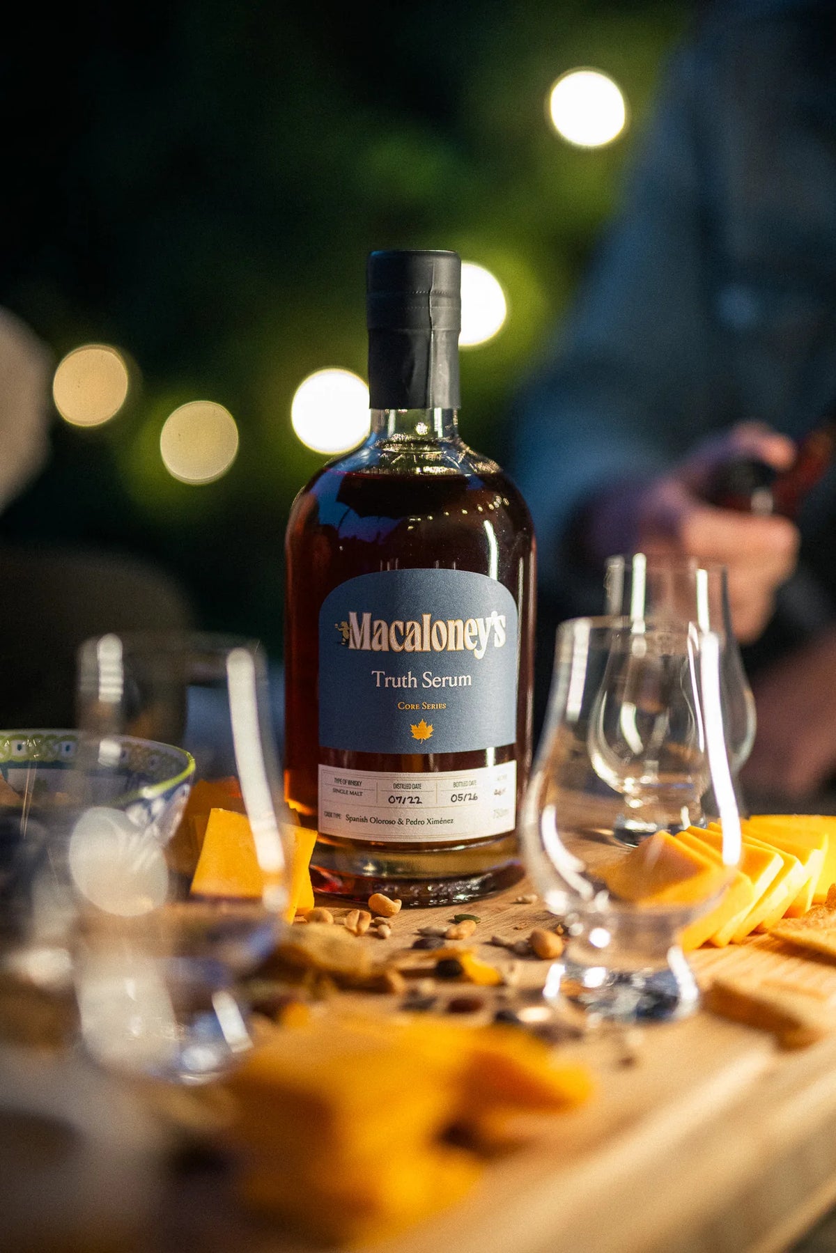 Macaloney's Truth Serum sherry cask single malt whisky on a grazing board under evening string lights